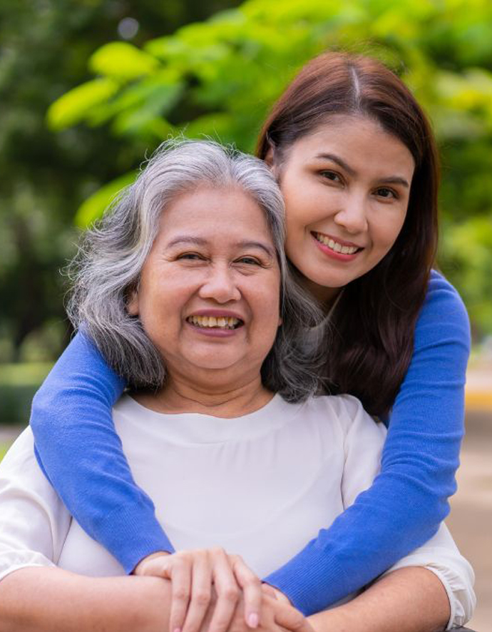 A daughter lovingly hugs her mother from behind