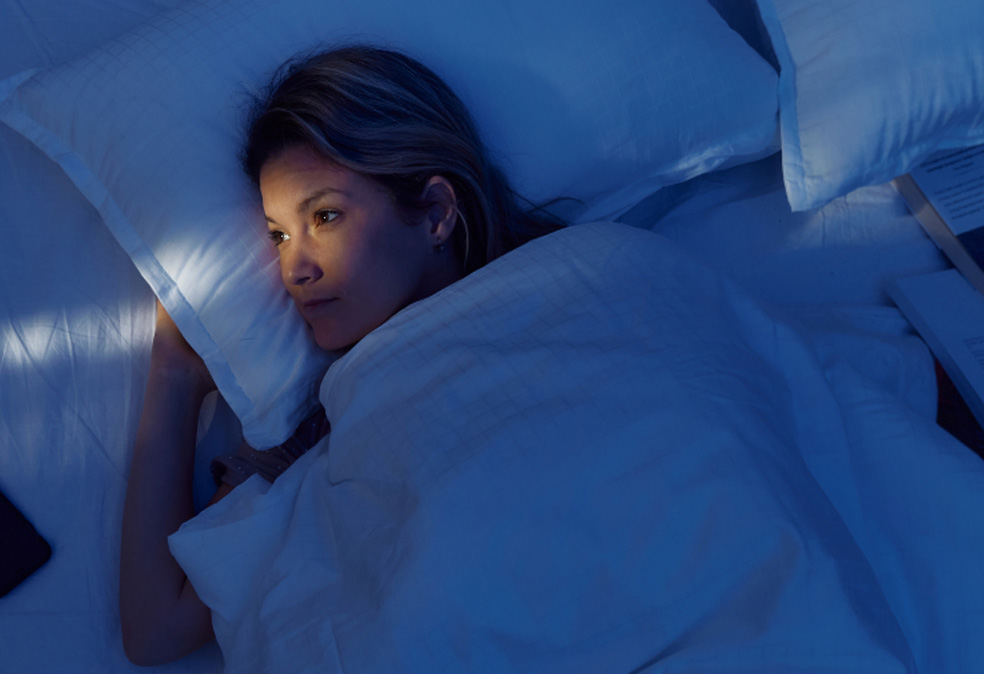 A woman lying awake in her bed at night.