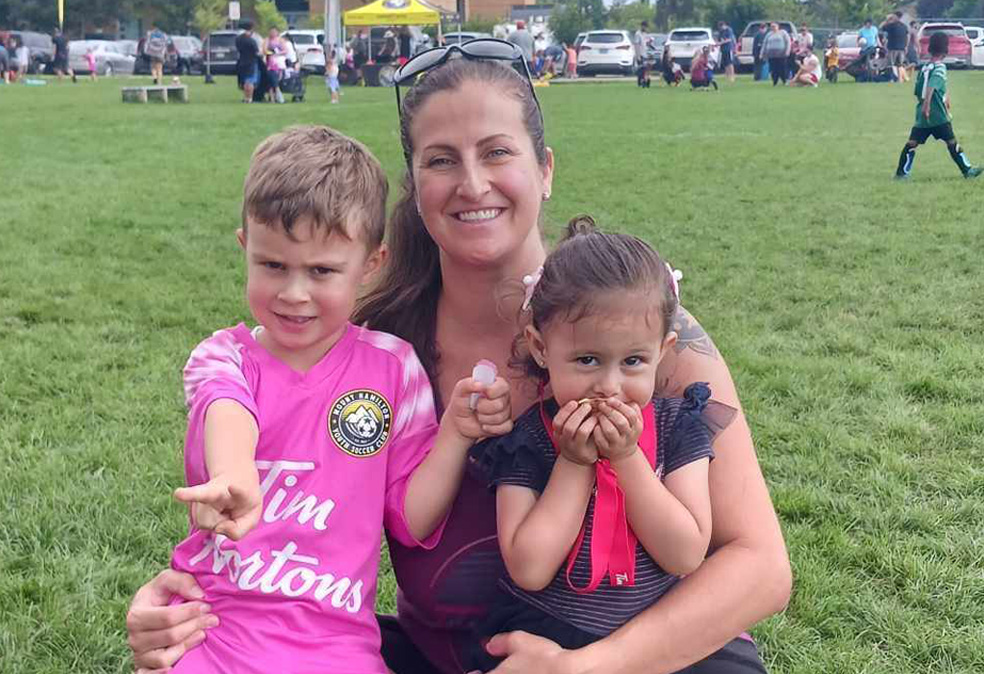 Amy Almas, a young mom, poses with her energetic children, a boy and a girl, on a soccer field