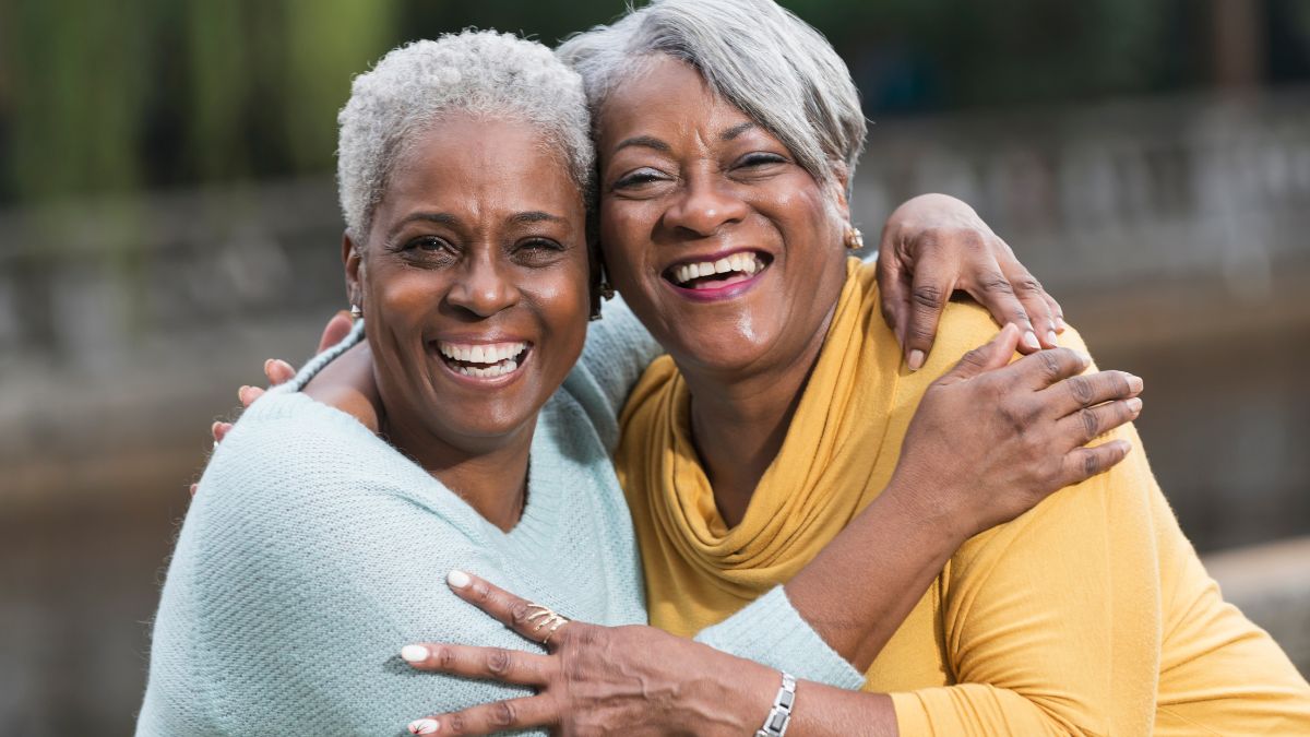 Two Black women hugging and smiling.