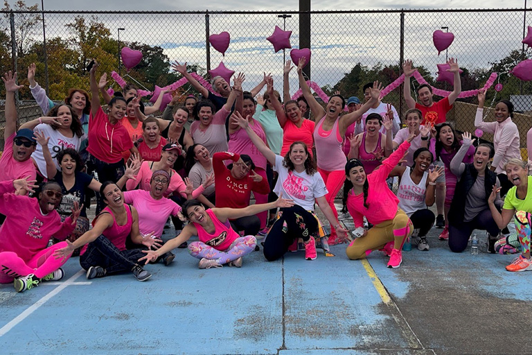 A large group of people wearing pink, gathered outside.