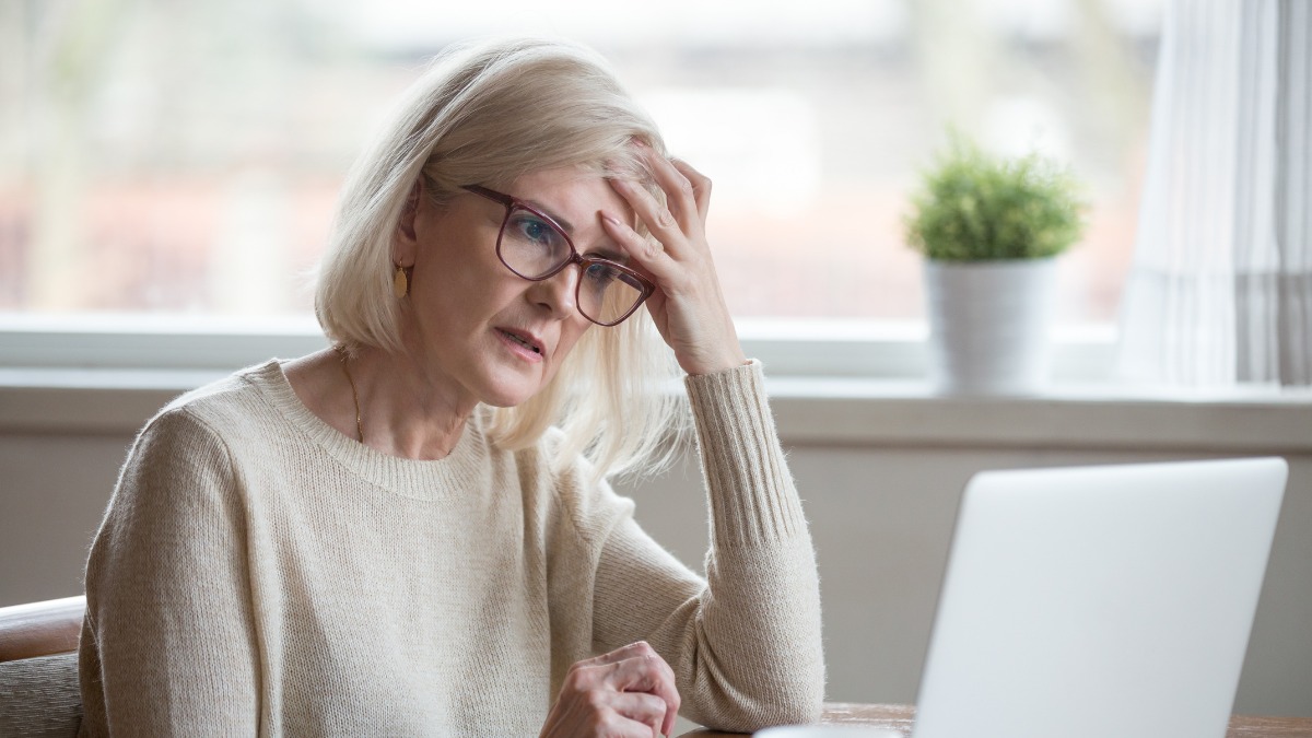 Older woman looking frustrated, staring at her laptop.