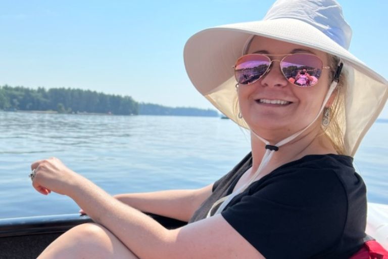 Jamie Gallagher wears a sun hat as she sits in a boat on a lake