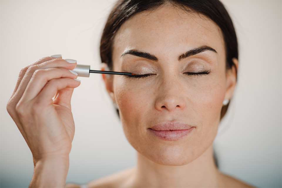 A woman applies a Maxeylash product to her eyelashes