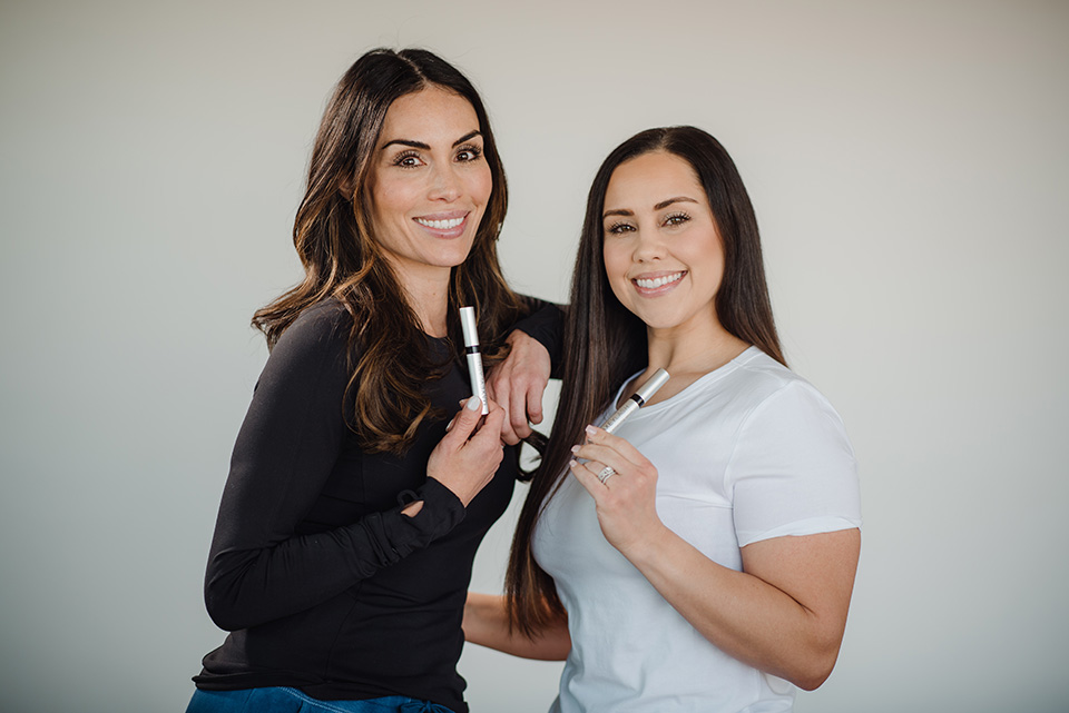 Two women holding Maxeylash products