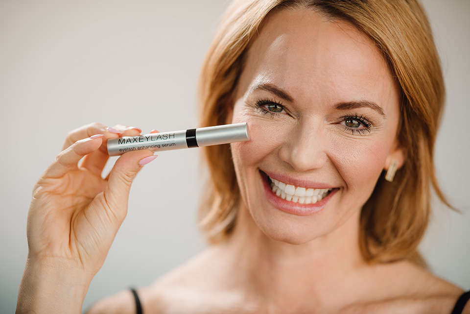 A woman holds a Maxeylash product