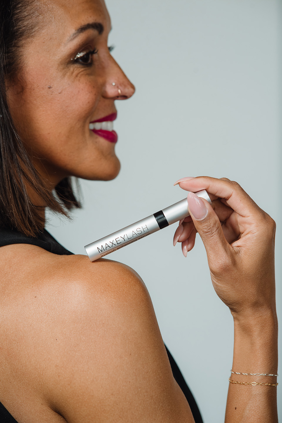 A woman holds a Maxeylash product