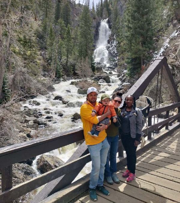 Camille Lewis and her caregivers in front of a waterfall during a trip