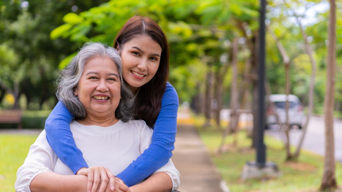 A daughter lovingly hugs her mother from behind