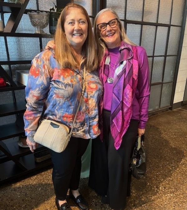 Lynn Folkman stands with her sister and caregiver Deb at an art event.