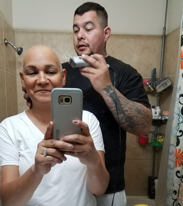 Miranda Gonzalez sits in a bathtub as her husband shaves her head.